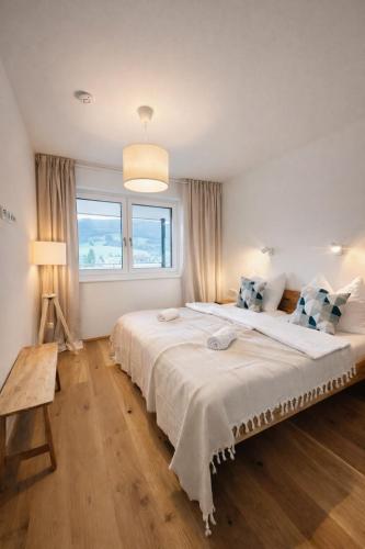 a white bedroom with a large bed and a window at Die Malerei Penthouse by Da Alois in Gröbming
