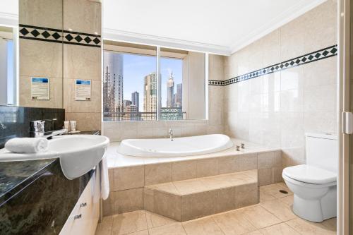a bathroom with a tub and a sink and a toilet at Clarion Suites Gateway in Melbourne
