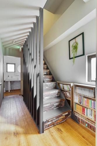 a staircase with bookshelves in a living room with a book shelf at Guesthouse YOURS in Osaka