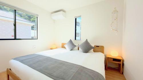 a white bedroom with a large bed and two windows at NAGI Resort Nago - Yofuke in Nago