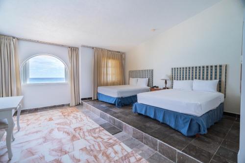 a hotel room with two beds and a window at Hotel y Museo Casa Turquesa in Cancún