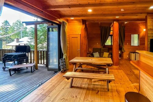 a wooden deck with a picnic table and a piano at るり渓森の宿 灯 akari in Nantan city