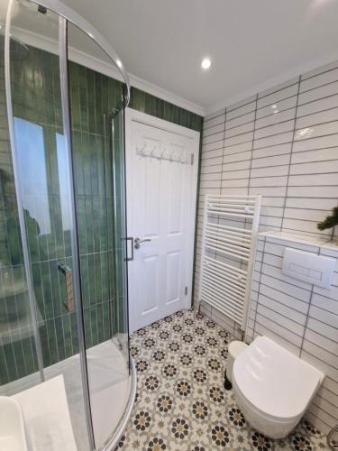a bathroom with a toilet and a glass shower at Justina's House in East Kilbride