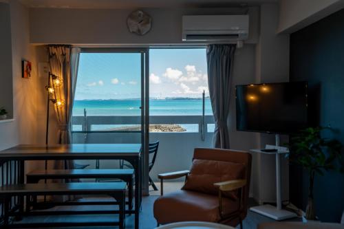 a living room with a table and a view of the ocean at Crest Blue 401-オーシャンフロント! 新築マンション! in Kin