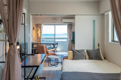 a bedroom with a bed and a table and a dining room at Crest Blue 401-オーシャンフロント! 新築マンション! in Kin