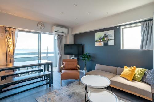 a living room with a couch and a table at Crest Blue 401-オーシャンフロント! 新築マンション! in Kin