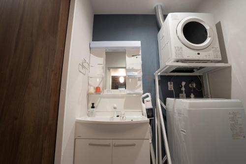 a bathroom with a sink and a washing machine at Crest Blue 401-オーシャンフロント! 新築マンション! in Kin