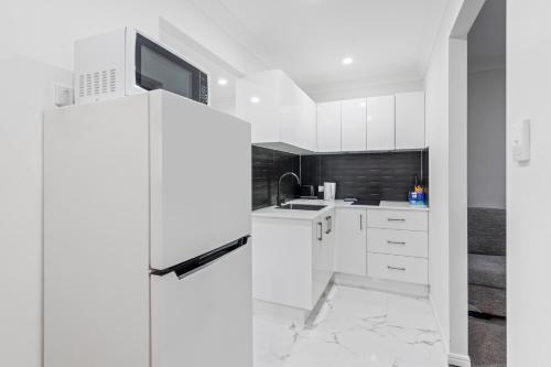 a white kitchen with a refrigerator and a sink at Forest view guesthouse in Runcorn