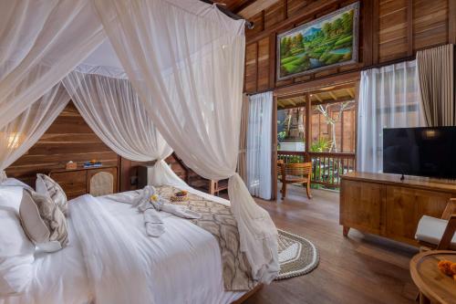 a bedroom with a white bed with a canopy at Kirani House - Joglo Villa Bali in Darmasaba