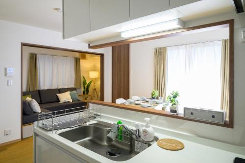 a kitchen with a sink and a living room at Chill Place 120 Ayase in Tokyo