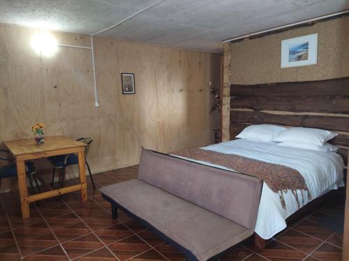 a bedroom with a bed and a table and a bench at Hostal Verde Vida in Futrono