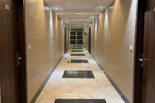 a hallway with a long corridor with doors and a tile floor at Hotel Beubelle in Meerut