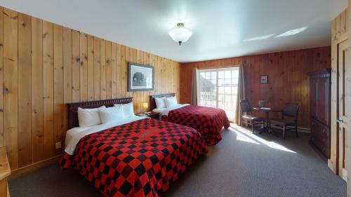 a hotel room with two beds and a table at Pourvoirie du Lac Blanc in Saint-Alexis-des-Monts