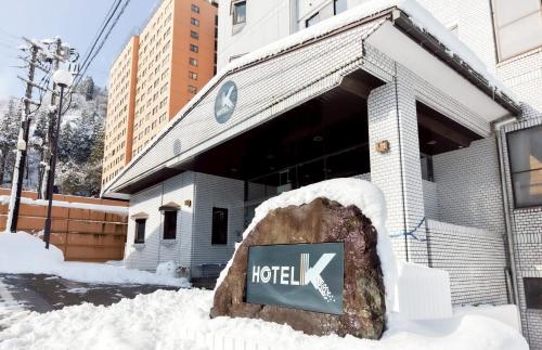 a sign in the snow in front of a hotel at Hotel K Yuzawa 越後湯澤溫泉旅館 in Yuzawa