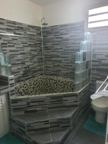 a bathroom with a tub with a toilet and a shower at Villa familiale pensé pour vous in Les Abymes