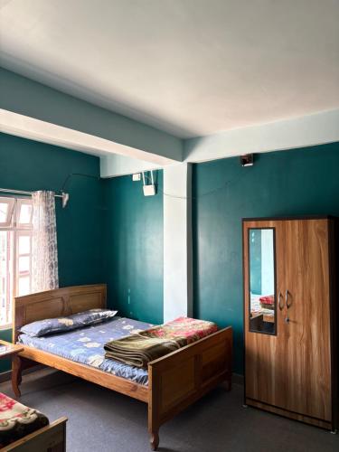 a bedroom with blue walls and a bed and a door at Sameer Homestay in Kalimpong