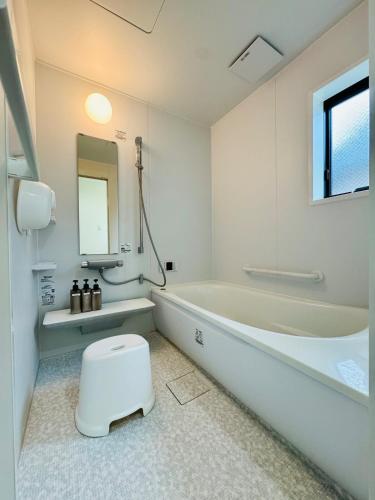 a white bathroom with a toilet and a bath tub at Villa 勝浦 in Katsuura