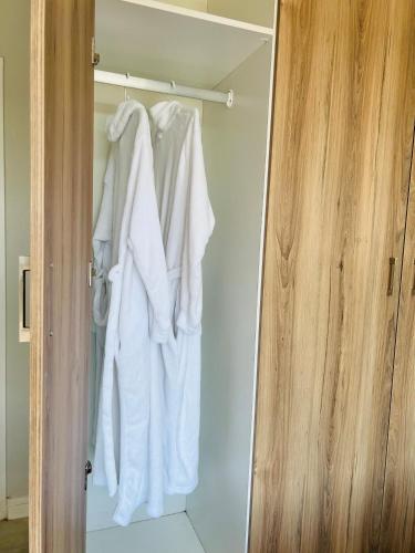 a closet with white clothes hanging in it at Lagoon Aparthotel in Pretoria