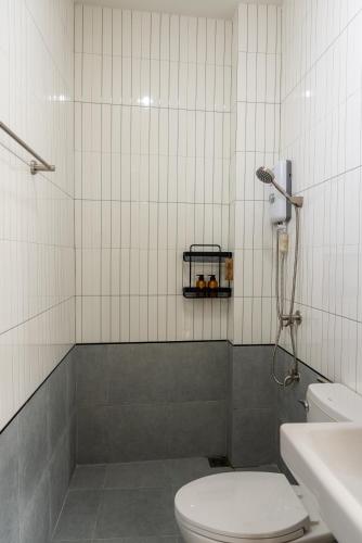 a white tiled bathroom with a toilet and a shower at Reach Home Hatyai in Hat Yai
