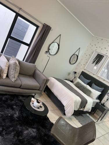 a bedroom with a bed and a couch and a clock at Lagoon Aparthotel in Pretoria