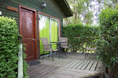 a wooden deck with chairs and a table on it at Cabañas Los Culenes in Colbún