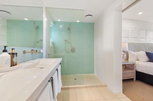 a bathroom with a sink and a shower and a bed at Waves #9 by Discover Stradbroke in Point Lookout