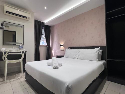a bedroom with a large white bed with a table at Q Inn by Pillow Plus in Petaling Jaya