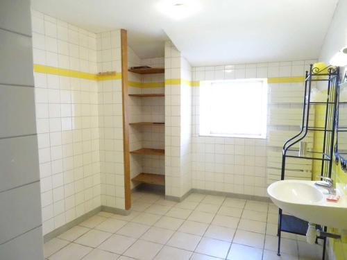 a white tiled bathroom with a sink and a window at L'étable aux deux noix in Arc-en-Barrois