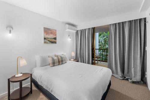 a white bedroom with a bed and a balcony at The Rocks Resort - Official in Gold Coast