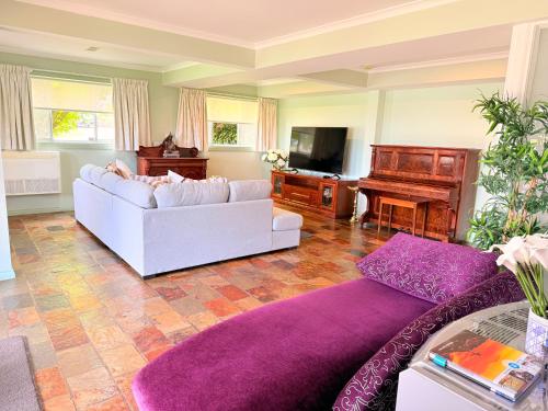 a living room with a couch and a piano at Spacious Apartment with the view of Mt. Wellington in Lenah Valley