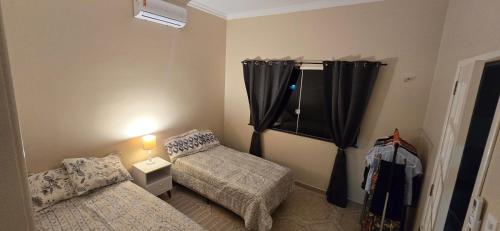 a small bedroom with two beds and a window at Base Luz na Floresta in Manaus