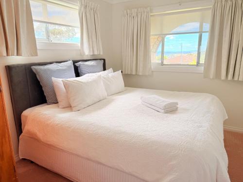 a bedroom with a large white bed with a window at Spacious Apartment with the view of Mt. Wellington in Lenah Valley