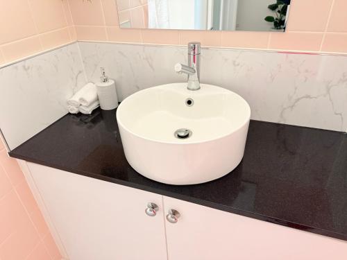 a white sink on a black counter in a bathroom at Spacious Apartment with the view of Mt. Wellington in Lenah Valley