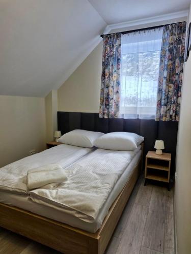 a bedroom with a large bed with a window at Domki Leśne Zacisze in Baczyn