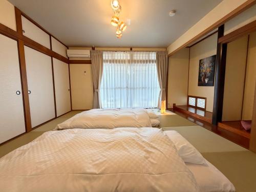 two beds in a bedroom with a window at かみくまハウス in Kumamoto