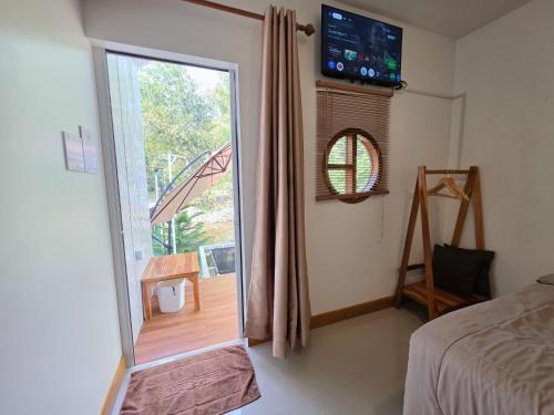a bedroom with a sliding glass door to a balcony at ไวท์ เฮ้าท์ แคมป์ ชะอม in Ban Bung Mai