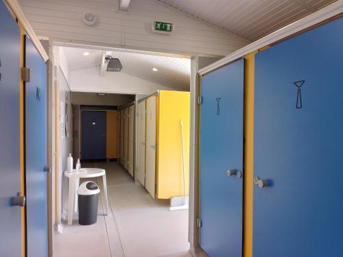 a hallway of a bathroom with yellow and blue doors at Camping Beausejour Sergines in Sergines