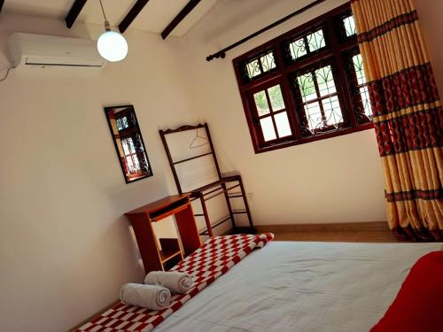 a bedroom with a bed and two windows at Mountain Bliss Villa Peradeniya in Peradeniya