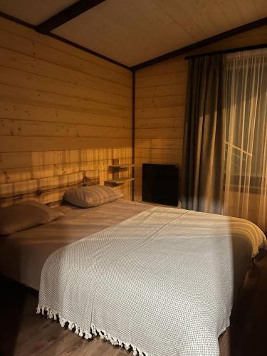 a bedroom with a white bed with a window at Nagoru house in Tukhlya