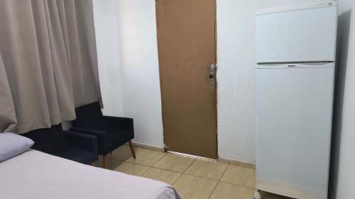 a room with a bed and a refrigerator and a chair at Pousada RC Q2 in Várzea Grande