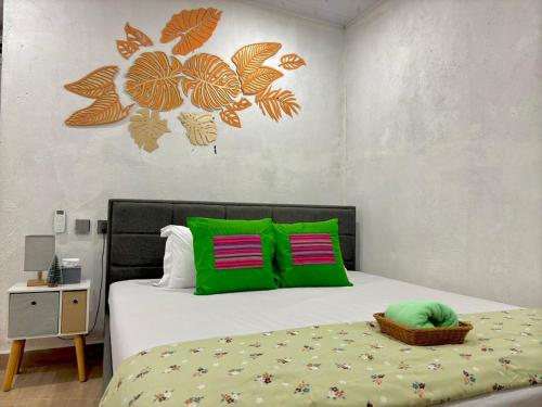 a bedroom with a bed with green and orange pillows at JE Garden Guesthouse in Oecusse RAEOA in Deli