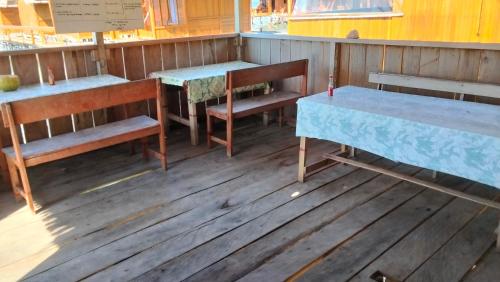 a row of tables and benches on a wooden floor at Adefiro Homestay in Besir