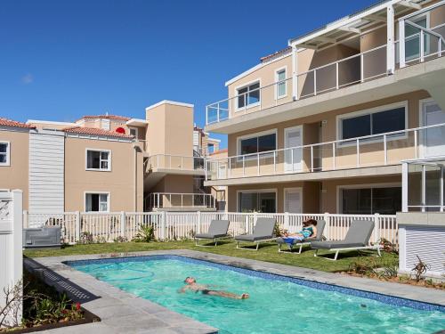 a person swimming in a swimming pool next to a building at Harbour Club in St Francis Bay