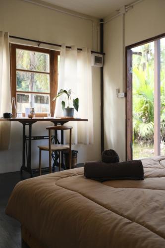 a bedroom with a bed and a table and a window at Baan Rim Len Koh Kood in Ko Kood