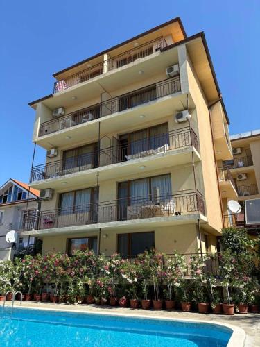 an apartment building with a swimming pool in front of it at Family Hotel Chris in Sveti Vlas