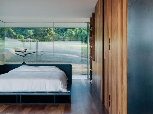 a bedroom with a bed and a large glass window at Triptych - The Glass House in Koonya