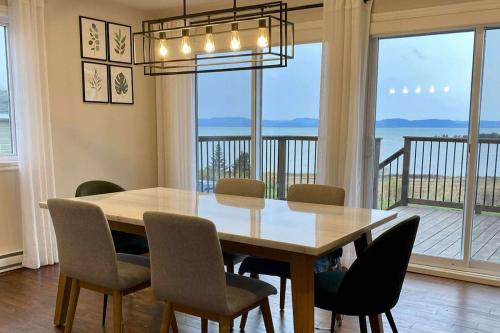 a dining room table and chairs with a view of the ocean at L'Anseau-Persil in Rivière-du-Loup