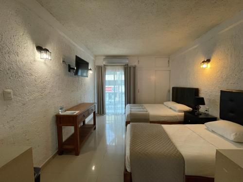a hotel room with two beds and a desk at Hotel Dos Mundos, Isla Cozumel in Cozumel