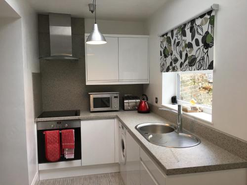 a kitchen with a sink and a microwave at Mildmay Road Apartments in London