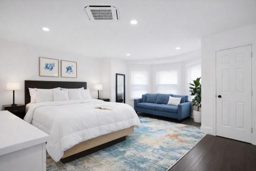 a white bedroom with a bed and a blue couch at West Philly Suites in Philadelphia